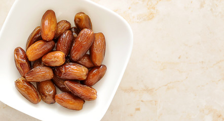 Dried dates fruit in a bowl, on a marble background
