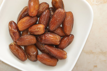 Dried dates fruit in a bowl, on a marble background