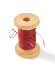 spool of thread and needle on white
