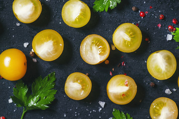 Food background of sliced yellow tomatoes cherry, dark backgroun
