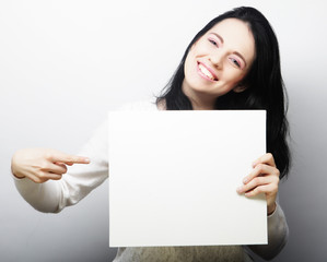 Fototapeta premium Smiling young casual style woman showing blank signboard