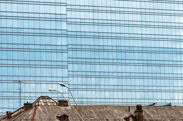 The roof of the old house on the background of ultra-modern buildings.
