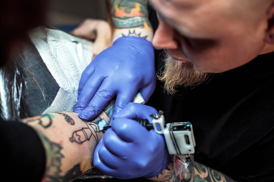 master tattooist makes a tattoo on the skin of the client in a workshop with special equipment