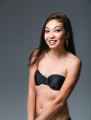 Shy woman in black underwear on studio background