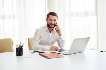 Fototapeta premium Man talking on the smartphone in the modern white office