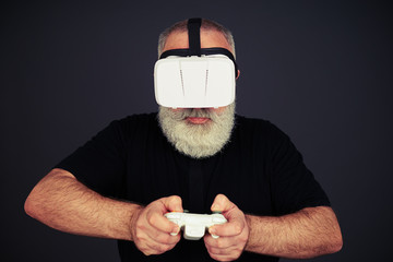 Senior man is playing on the joystick wearing hi-tech VR headset