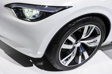 Obraz na płótnie Canvas Car headlight and wheel with silver disk of comfortable sport sedan with white bodywork, luxury class vehicle