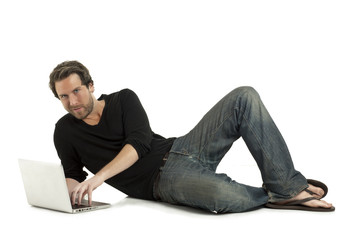 relaxed man lying on the floor using a laptop