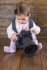 Bebé fotógrafo con una cámara réflex profesional ajustando parámetros para hacer una...