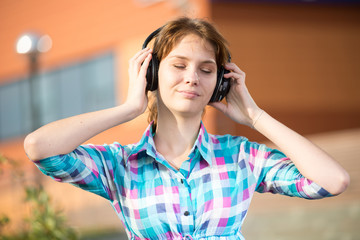 Fototapeta premium Young beautiful girl listening to music player on the street. tudent woman at campus park.