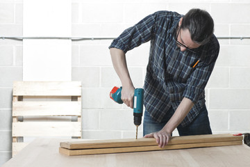 man drilling piece of wood