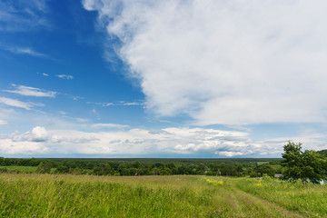 Countryside natural background. Rural path winds along the field. Cloudscape in sunny day. Russia.
