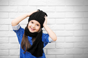 Little girl on a white brick wall background