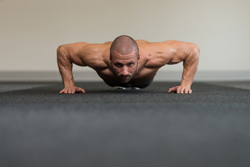 Fototapeta na wymiar Young Bodybuilder Exercising Press Ups On Floor