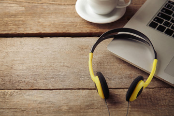 Laptop and earphones on wooden background