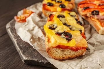 Hot pizza baguette with paprika, olives and cheese on wooden table