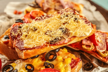 Hot pizza baguette with salami, mushrooms and cheese on wooden table