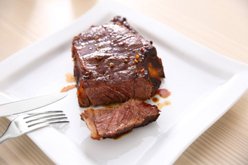 Sliced roasted pork steak with cutlery on white plate