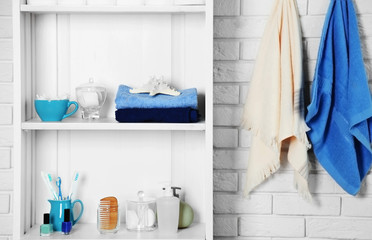 Bathroom set with towels, toothbrushes and sponges on a shelf in light interior