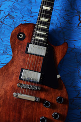 Fototapeta na wymiar Brown electric guitar on blue wooden background