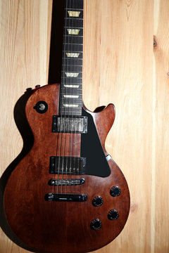 Brown electric guitar on wooden background