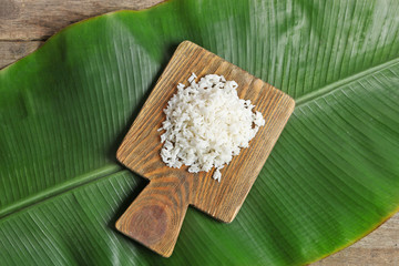 Boiled rice on banana leaf over wooden background