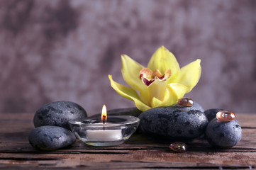 Spa still life with stones, flower and candlelight on blurred pastel background
