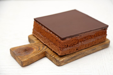 Delicious chocolate cake on wooden cutting board isolated on white