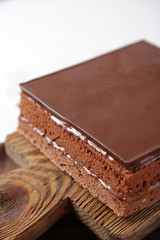 Delicious chocolate cake on wooden cutting board closeup