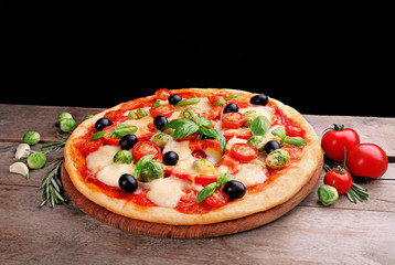 Delicious pizza with cheese and vegetables on black background
