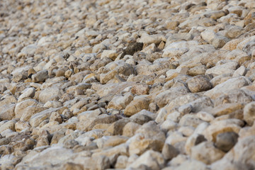 White yellow brown big and small natural stones levee at Dead Sea background