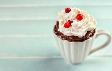 Mug cake with cream and cranberry on blue wooden background