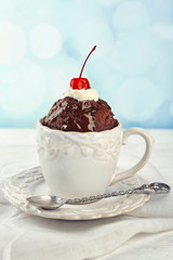 Chocolate mug cake with cream and cherry on a table
