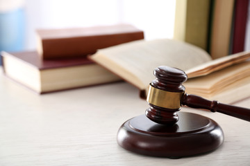 Gavel with books on wooden table closeup