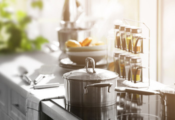 Modern table and electric stove with utensils and spices in the kitchen beside window