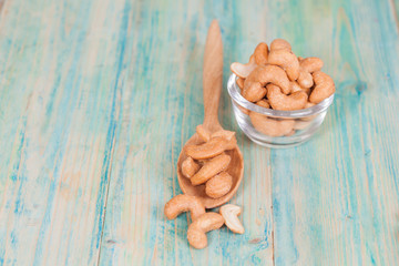 Cashew nuts in spoon, on the wooden
