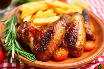 Baked chicken wings with French fries, close up