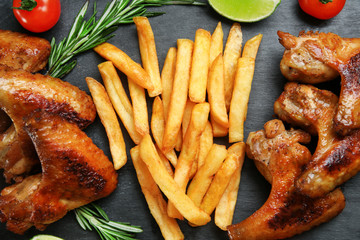 Baked chicken wings with French fries on slate plate