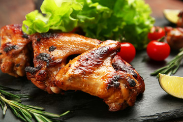 Baked chicken wings with vegetables on slate plate