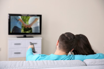 Young couple watching TV on a sofa at home