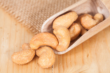Cashew nuts in spoon, on the wooden