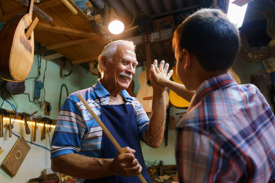 Senior Man Lute Maker Teaching Boy Chiseling Wood
