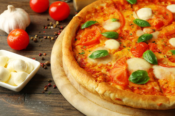 Margherita pizza with tomatoes, garlic, spices and Mozzarella on wooden background