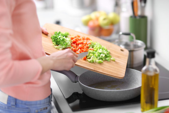 Woman frying vegetables in kitchen