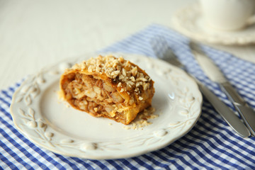 Slice of strudel with apples, walnut and raisins on white plate