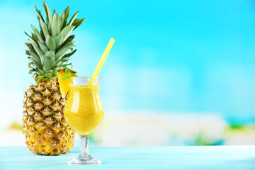 Pineapple smoothie in cocktail glass with slices on blue blurred background