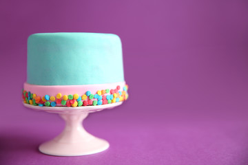 Birthday cake with sprinkles on purple background.