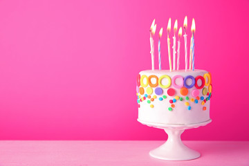 Birthday cake with candles on pink background.