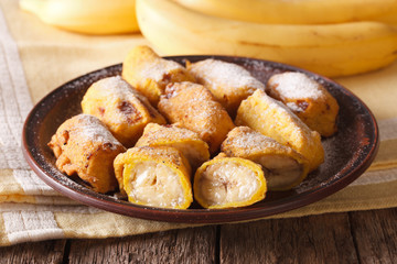 Traditional fried bananas sprinkled with powdered sugar close-up. horizontal
