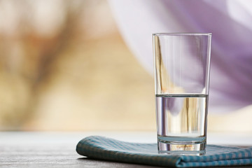 Glass of water with napkin  on light background
